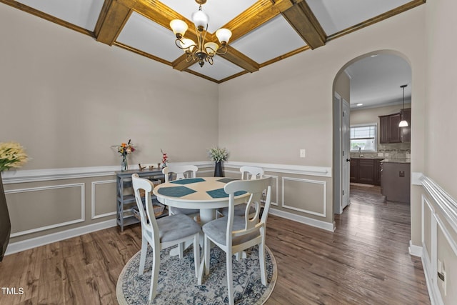 dining area with arched walkways, a decorative wall, and dark wood-style flooring