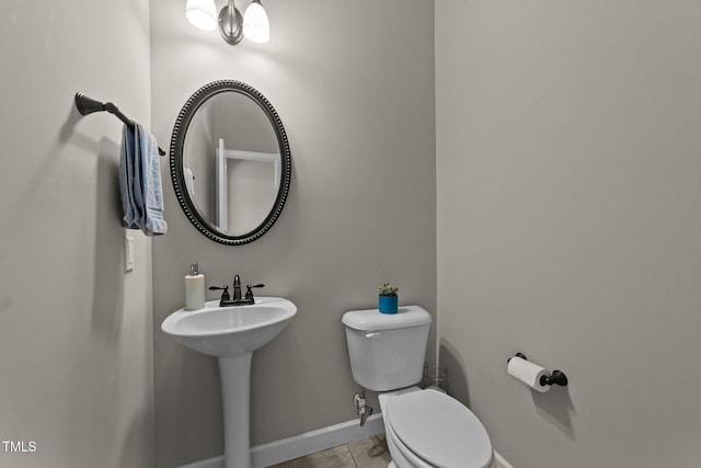half bath with toilet, tile patterned floors, and baseboards