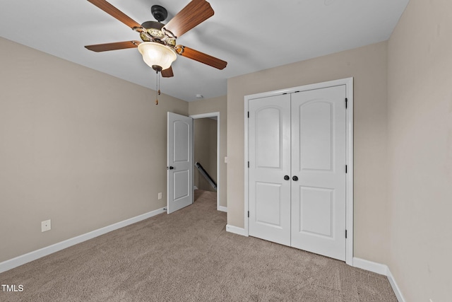 unfurnished bedroom featuring carpet floors, baseboards, a closet, and ceiling fan