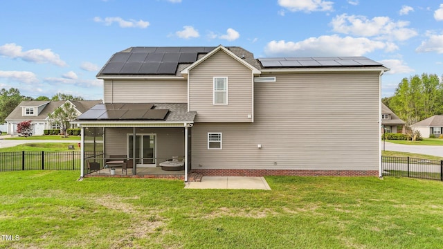 back of property with a yard, a patio area, a sunroom, and roof mounted solar panels