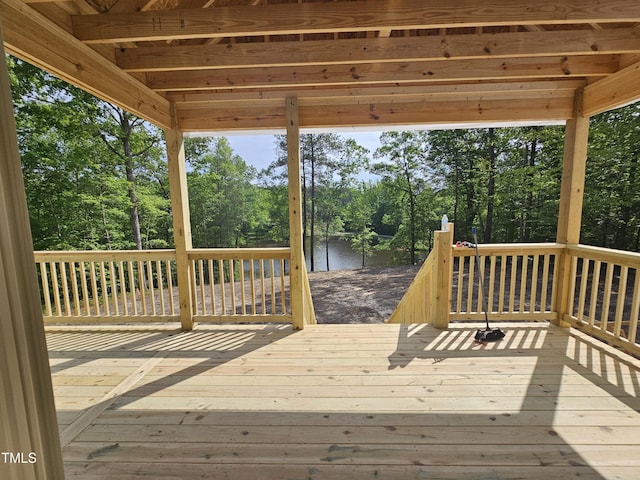 wooden deck with view of wooded area and a water view