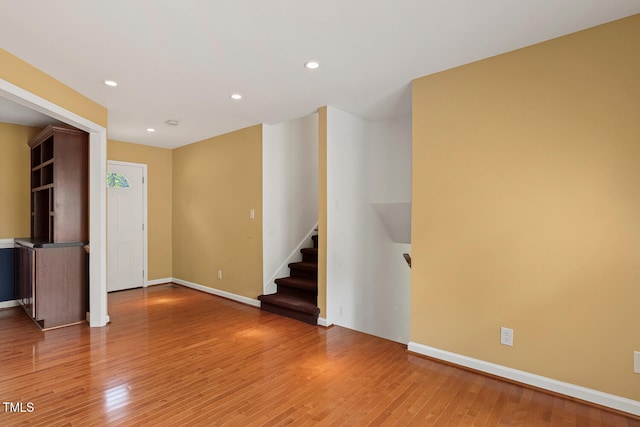 unfurnished living room with light wood-style flooring, stairway, and recessed lighting