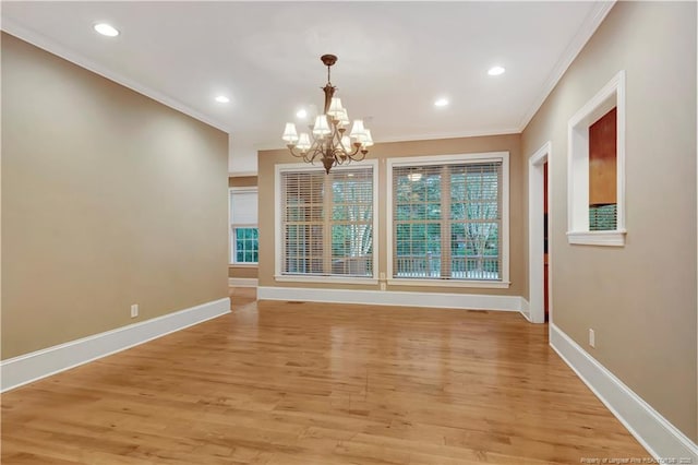 unfurnished dining area featuring light wood finished floors, baseboards, crown molding, and a chandelier