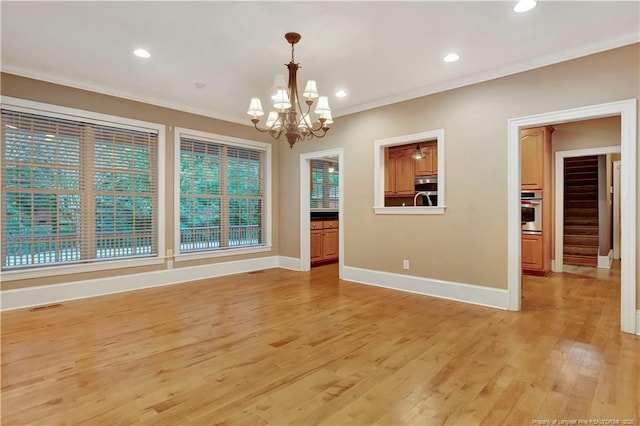 interior space with crown molding, an inviting chandelier, baseboards, light wood-style floors, and visible vents