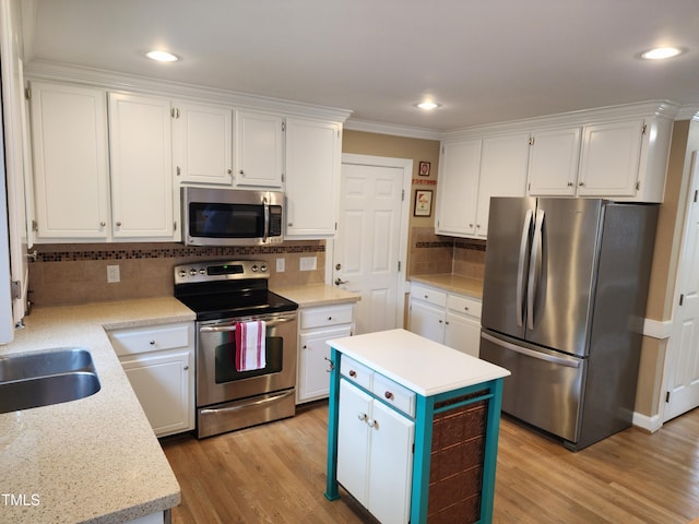 kitchen with appliances with stainless steel finishes, white cabinets, tasteful backsplash, light wood-style flooring, and light countertops