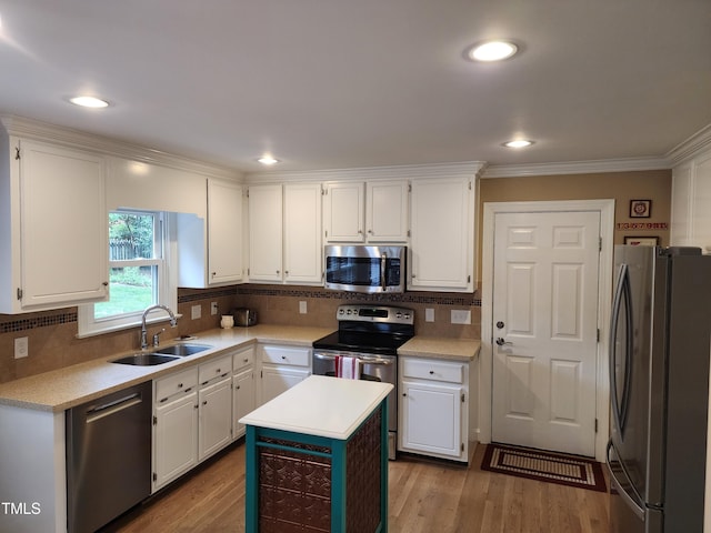kitchen with stainless steel appliances, a sink, white cabinetry, crown molding, and light countertops