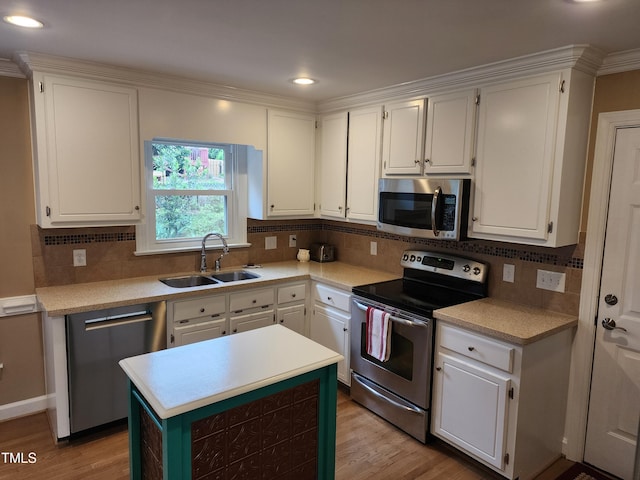 kitchen with stainless steel appliances, a sink, light wood-style floors, white cabinets, and recessed lighting
