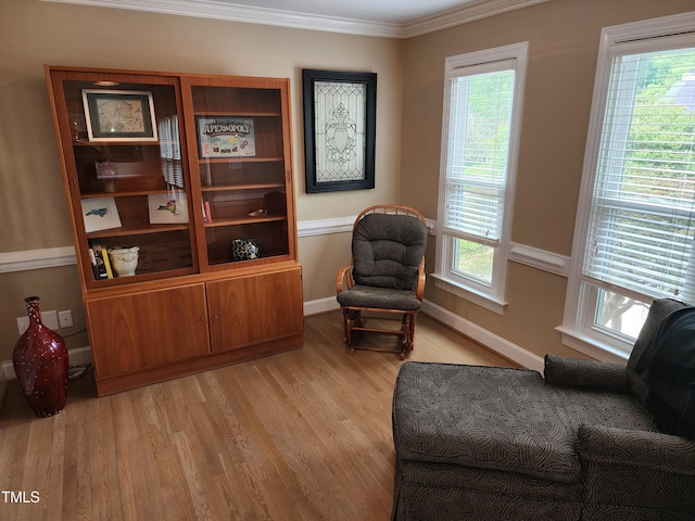 sitting room featuring light wood-type flooring, healthy amount of natural light, crown molding, and baseboards