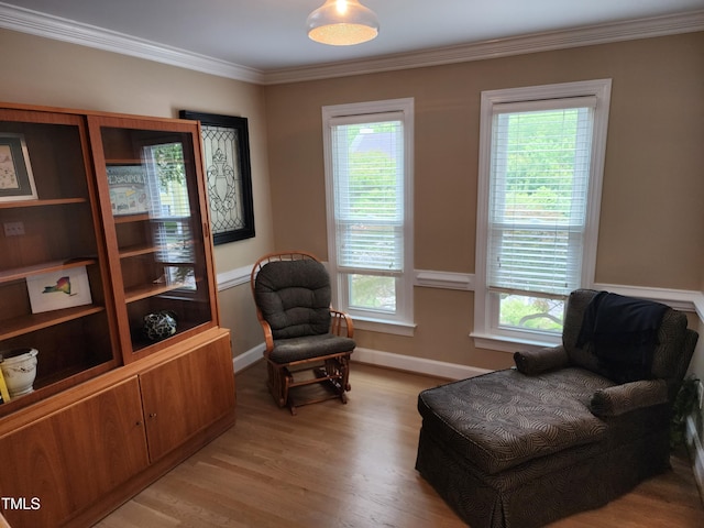 living area featuring healthy amount of natural light, crown molding, baseboards, and light wood finished floors