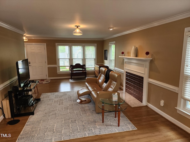 living area with crown molding, wood finished floors, a fireplace with flush hearth, and baseboards