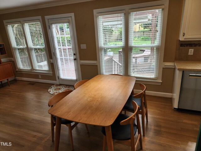 dining room featuring crown molding, baseboards, and wood finished floors