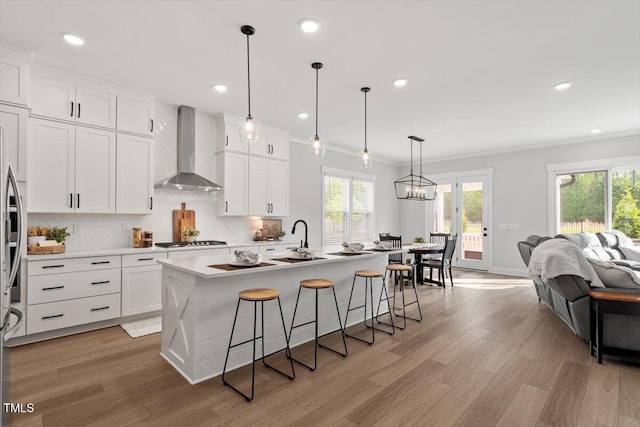 7616 Hasentree Way, Wake Forest, NC 27587 - kitchen featuring wall chimney range hood, backsplash, stainless steel gas stovetop, and light wood-style flooring