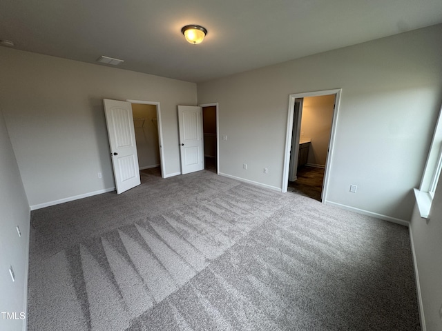 168 Bruce Dr, Dunn, NC 28334 - unfurnished bedroom featuring carpet flooring, a walk in closet, connected bathroom, and a closet
