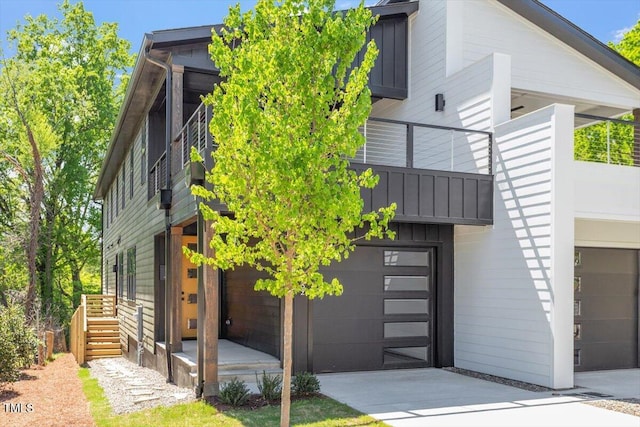 exterior space featuring concrete driveway, an attached garage, board and batten siding, and a balcony