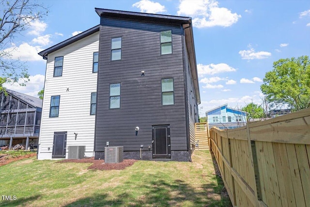 back of house with a lawn, central AC, fence, and a sunroom