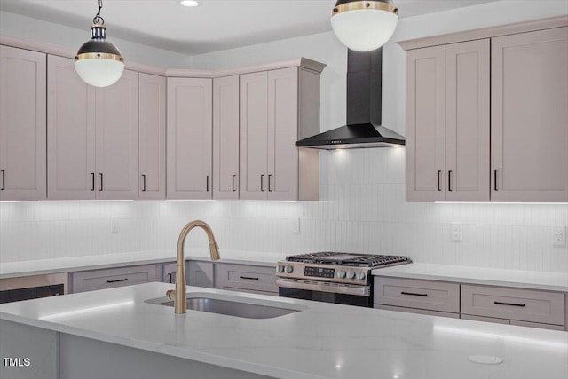 kitchen with wall chimney range hood, gas range, hanging light fixtures, light stone countertops, and a sink