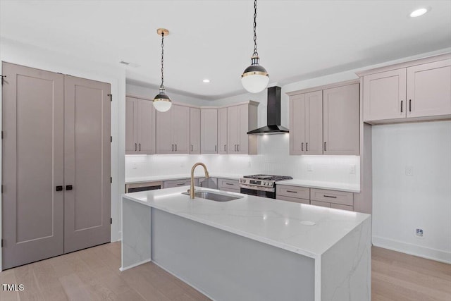 kitchen with backsplash, stainless steel gas range oven, light wood-type flooring, a sink, and wall chimney exhaust hood