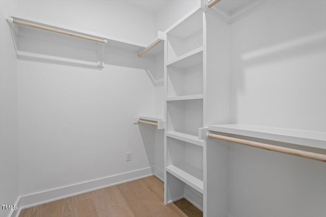 walk in closet with wood finished floors