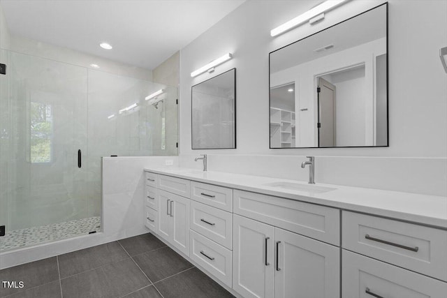 bathroom with a sink, tile patterned floors, a shower stall, and double vanity