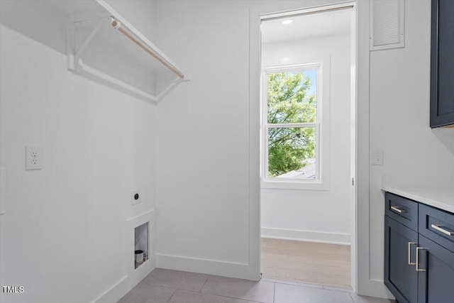 washroom featuring cabinet space, light tile patterned flooring, electric dryer hookup, and baseboards