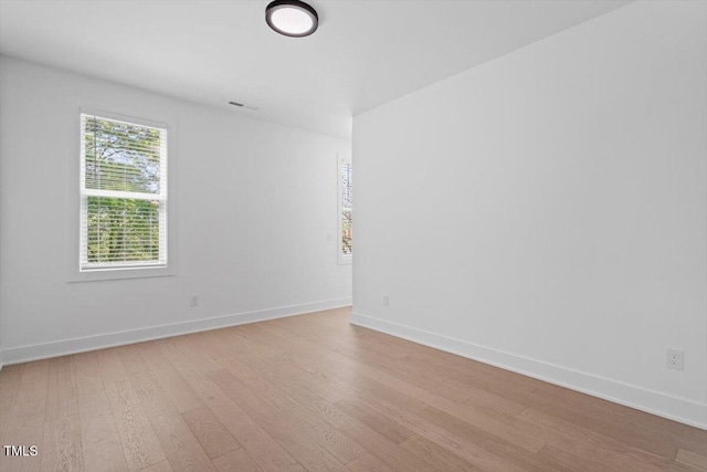 empty room featuring baseboards, light wood-type flooring, and visible vents
