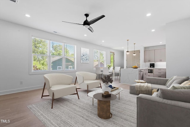 living room with visible vents, baseboards, ceiling fan, recessed lighting, and light wood-style flooring