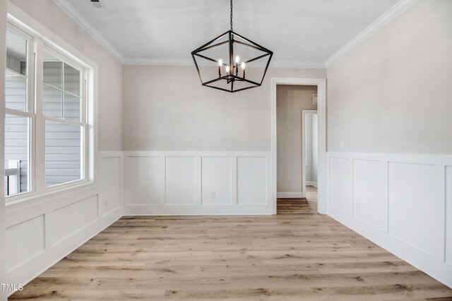 186 Gumtop Dr, Zebulon, NC 27597 - unfurnished dining area with a chandelier, crown molding, a decorative wall, light wood-type flooring, and a wainscoted wall