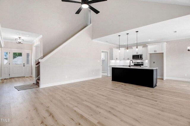 186 Gumtop Dr, Zebulon, NC 27597 - unfurnished living room with ornamental molding, stairs, light wood-style flooring, baseboards, and a ceiling fan