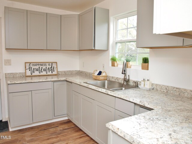 kitchen with light countertops, a sink, light wood-style floors, and gray cabinetry