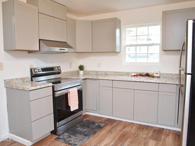 kitchen featuring gray cabinetry, under cabinet range hood, light wood-style flooring, and appliances with stainless steel finishes