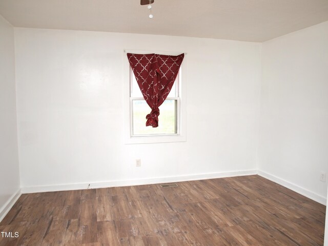 empty room featuring baseboards, visible vents, and wood finished floors