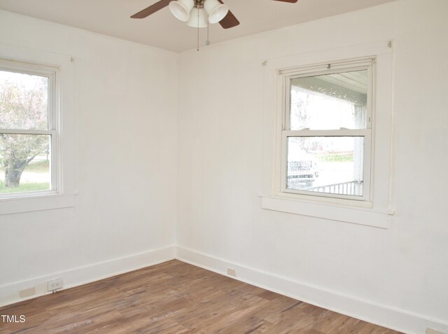 spare room featuring a healthy amount of sunlight, wood finished floors, and a ceiling fan