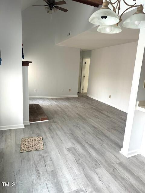 unfurnished living room featuring baseboards, high vaulted ceiling, wood finished floors, and a ceiling fan