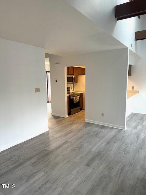 unfurnished living room featuring baseboards and wood finished floors