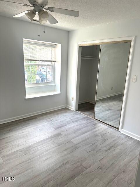 unfurnished bedroom featuring baseboards, a closet, wood finished floors, and a textured ceiling