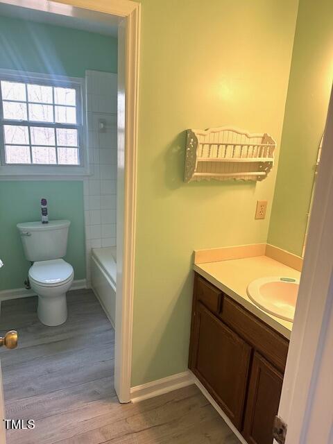 full bath featuring toilet, wood finished floors, baseboards, and vanity
