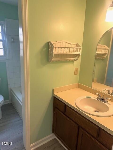 full bath featuring baseboards, wood finished floors, toilet, and vanity