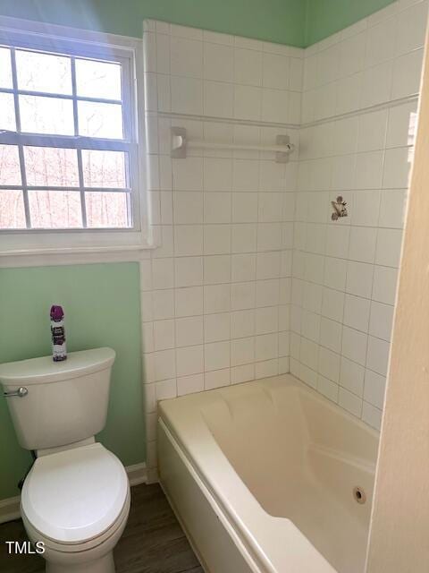 bathroom featuring toilet,  shower combination, baseboards, and wood finished floors