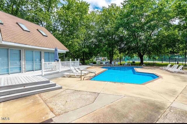 community pool with fence and a patio area