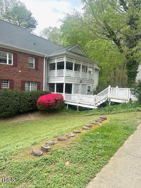 back of house with a lawn and brick siding