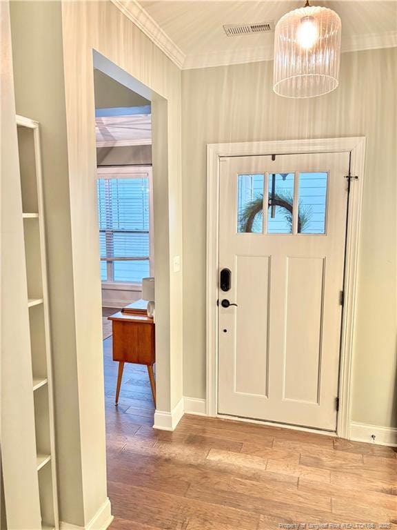entryway featuring visible vents, a chandelier, baseboards, ornamental molding, and wood finished floors