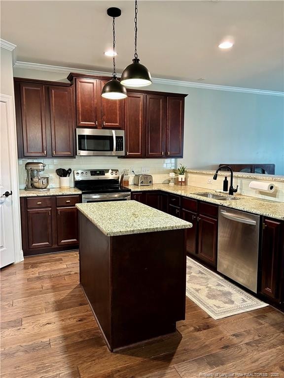 kitchen with dark wood-style flooring, a sink, stainless steel appliances, and crown molding