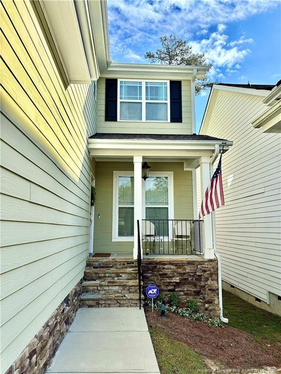 view of exterior entry with crawl space and covered porch