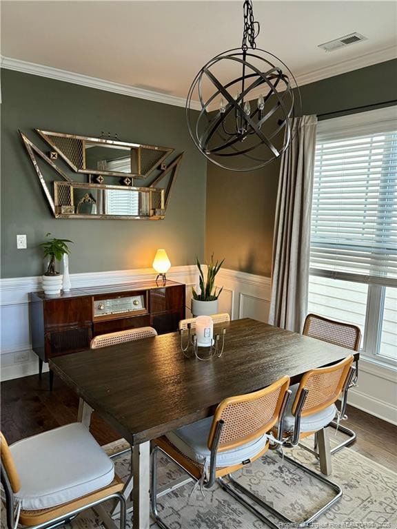 dining space with visible vents, wood finished floors, a chandelier, and crown molding