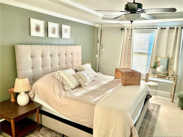 carpeted bedroom with crown molding, a raised ceiling, and a ceiling fan