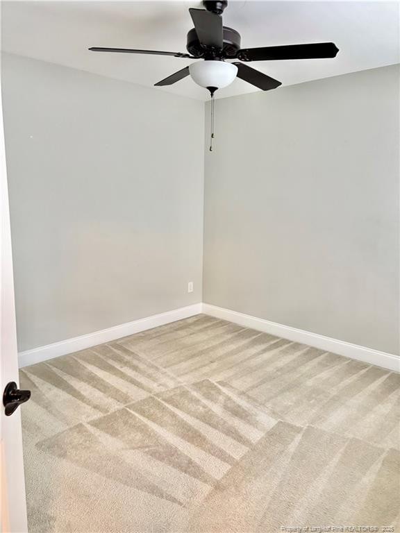 empty room featuring baseboards, light colored carpet, and ceiling fan