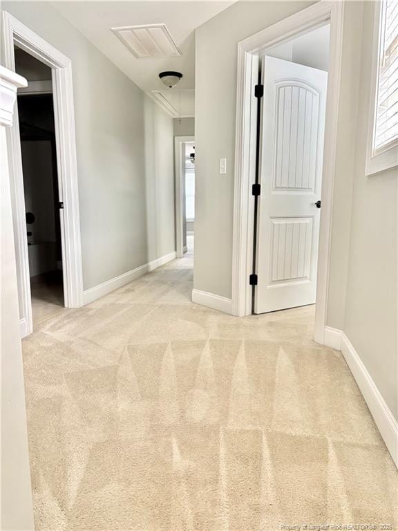 hall with baseboards, carpet, and attic access