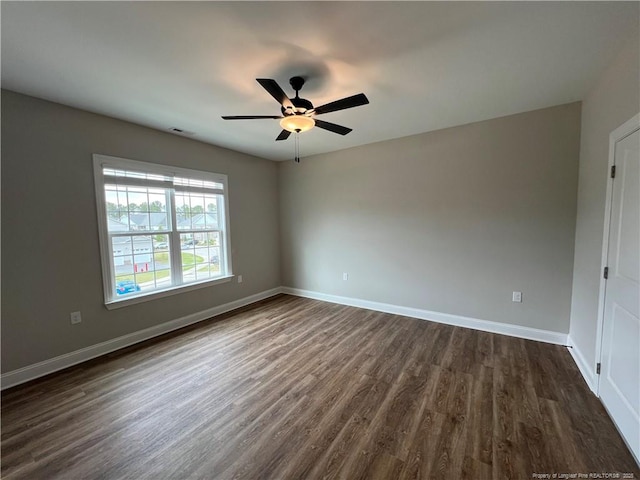 unfurnished room with baseboards, dark wood-style floors, visible vents, and a ceiling fan