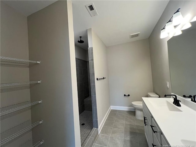 bathroom featuring visible vents, toilet, vanity, and a tile shower