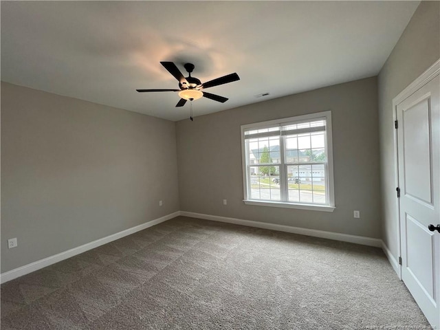 carpeted spare room featuring baseboards, visible vents, and a ceiling fan